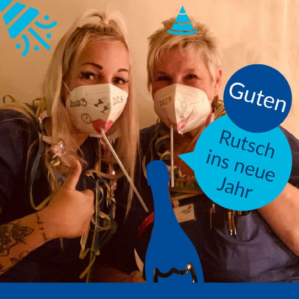 Im Bild sieht man zwei Mitarbeiterinnen unseres Krankenhauses, welche Konfetti und Dekorationen um den Hals haben. Sie haben verzierte Masken auf. Im Text steht: "Guten Rutsch ins neue Jahr."
